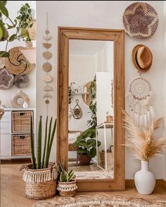 a mirror sitting on top of a wooden floor next to potted plants and baskets