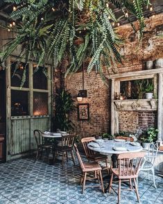 an outdoor dining area with brick walls and potted plants hanging from the ceiling above