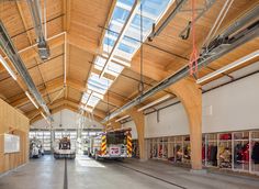 the inside of a fire station with two trucks and ladders on either side of the building