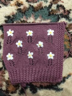 a purple knitted bag with white flowers on it