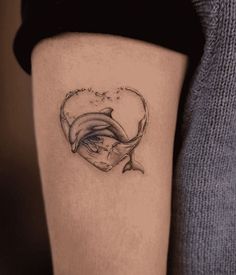 a woman's thigh with a dolphin tattoo on her left leg and a heart in the middle