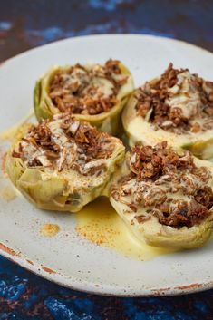 four stuffed cabbages on a white plate with sauce drizzled over them