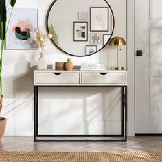 a table with a mirror, vase and plants on it