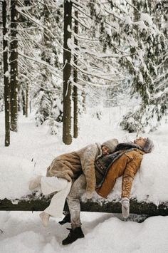 a man laying on top of a log in the snow