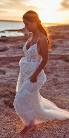 a woman in a white dress walking on the beach