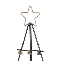 a black and gold metal star on a tripod with two bells in the middle