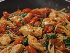 chicken, tomatoes and spinach stir fry in a wok