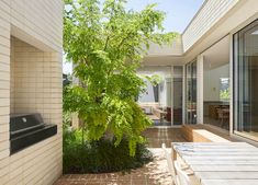 an outdoor dining area with wooden table and bench, surrounded by greenery on either side