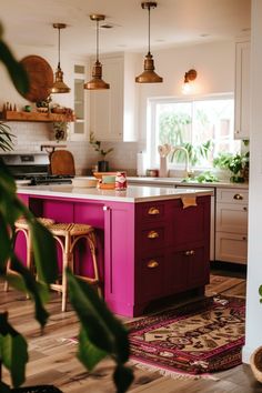 a kitchen with white cabinets and pink island