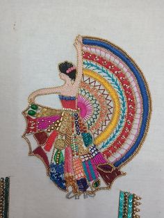 an embroidered piece of cloth with a woman in the center and colorful designs on it