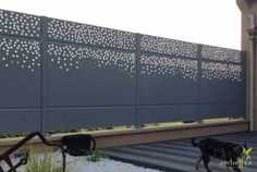 a black dog is standing in front of a fence with snow on the ground next to it