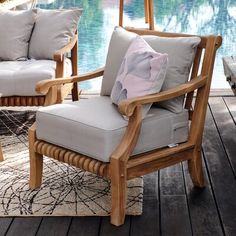 two wooden chairs sitting next to each other on top of a wooden floor near a swimming pool