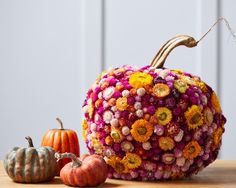 a pumpkin made out of flowers sitting on top of a table next to two small pumpkins