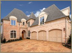 a large brick house with two garages and three windows