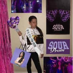 a young woman holding flowers and posing for a photo in front of purple backdrops