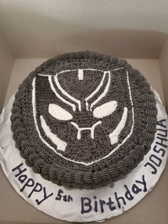 a black and white birthday cake with an angry face on it's side in a box