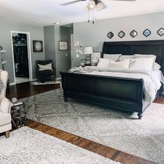 a large bed sitting in the middle of a living room next to a white chair