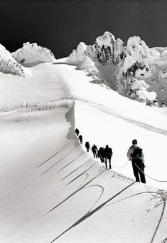 a group of people walking up the side of a snow covered slope