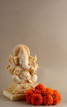 there is an orange flower next to the small statue and it looks like ganesh