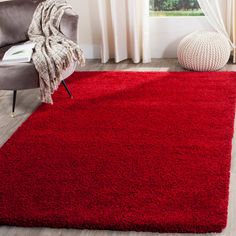 a red area rug in a living room with a chair and window behind the rug