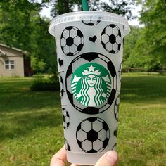 someone holding up a starbucks cup with soccer balls on it