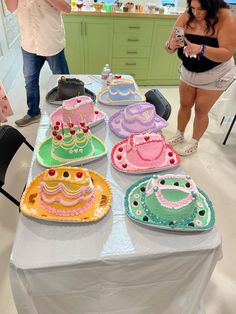 people standing around a table with cakes on it