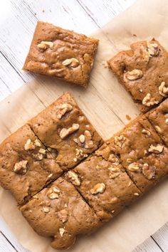 some brownies are cut into squares and placed on a piece of parchment paper with walnuts