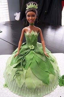 a doll in a green dress sitting on top of a table