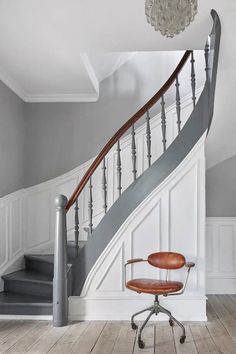 an office chair sitting in front of a stair case next to a chandelier