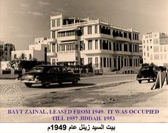 a black and white photo of cars driving down the street in front of a building