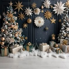 there are many christmas trees and presents in front of the wall with gold stars on it