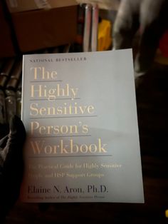 a person holding up a book about the highly sensitive person's workbook in their hand