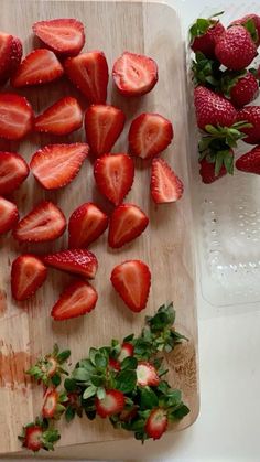 sliced strawberries on a cutting board next to some water