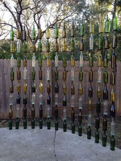 many wine bottles are hanging from a wooden fence