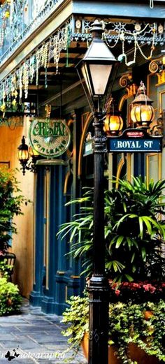 a lamp post in front of a building with lots of plants and lights on it