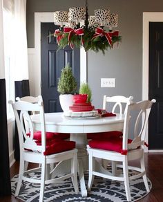 a white table with red chairs around it and a potted plant on the top