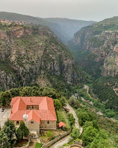 an aerial view of a house in the middle of a valley with mountains behind it