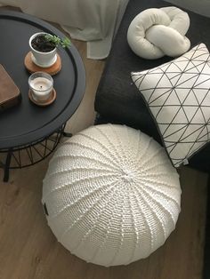 a living room with black furniture and white pillows on the floor, along with a coffee table