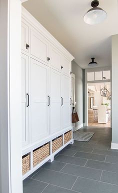 a hallway with white cabinets and baskets on the floor