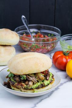 a sandwich sitting on top of a white plate next to tomatoes and other food items