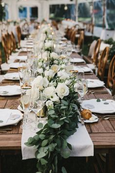 a long table is set with white flowers and greenery for an elegant wedding reception