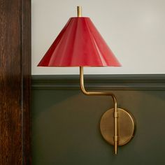 a red lamp sitting on top of a green wall next to a wooden frame and door