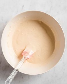 a bowl with a whisk in it sitting on a table next to a spoon