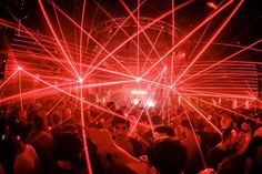 people are dancing with laser lights in the dark