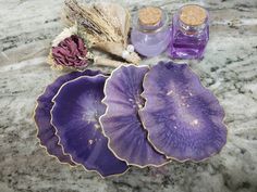 three purple dishes sitting on top of a marble counter next to lavender bottles and dried flowers