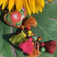 the sunflower is next to some tassels and beads on a green leaf