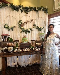 a woman standing in front of a table with cakes and desserts on top of it