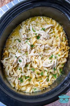 a crock pot filled with chicken noodle soup and garnished with parsley