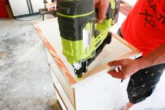 a man using a cordless drill to attach a piece of wood on top of a table