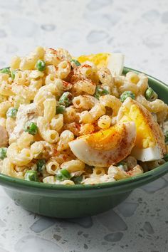 a green bowl filled with macaroni and cheese salad on top of a table